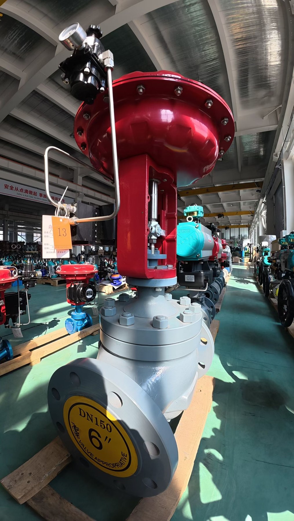 Large red industrial control valve in a manufacturing workshop
